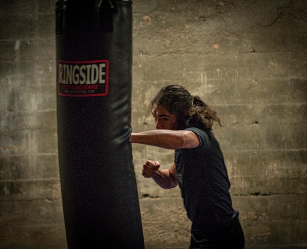 a woman in black shirt and black shorts hitting a punching bag