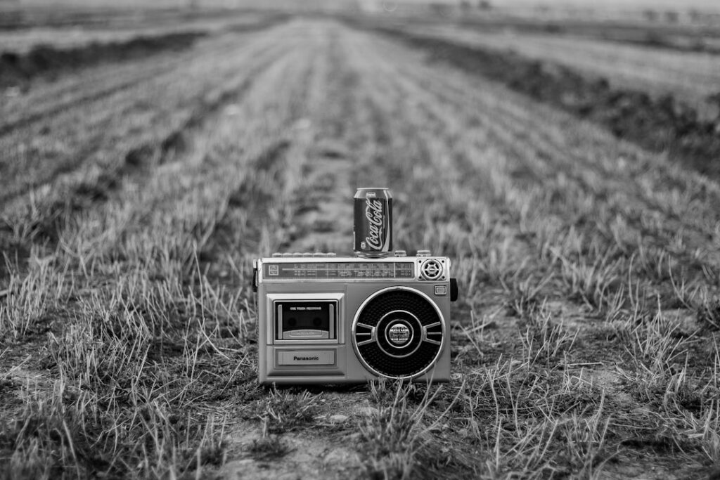 a radio in a field with a can of soda on top of it