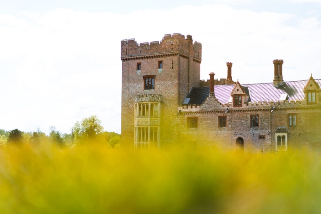 an old castle with a clock tower in the middle of a field