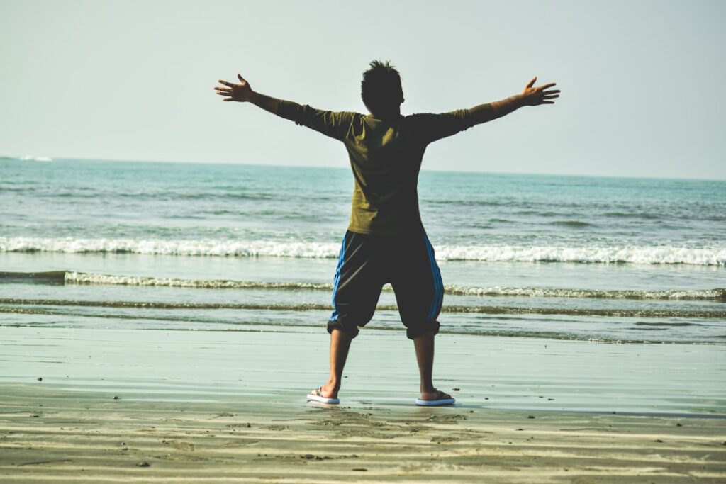 woman in black shirt and blue shorts jumping on beach during daytime