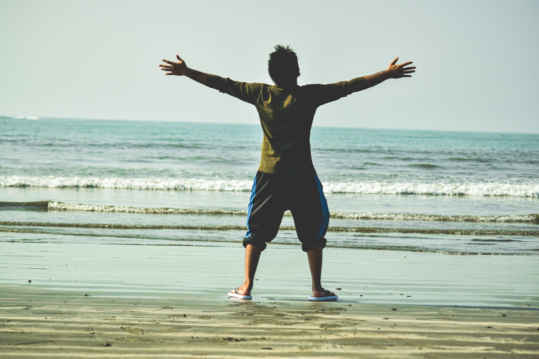 woman in black shirt and blue shorts jumping on beach during daytime