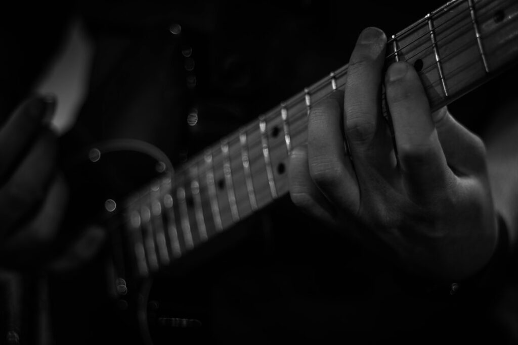 person playing guitar in grayscale photography