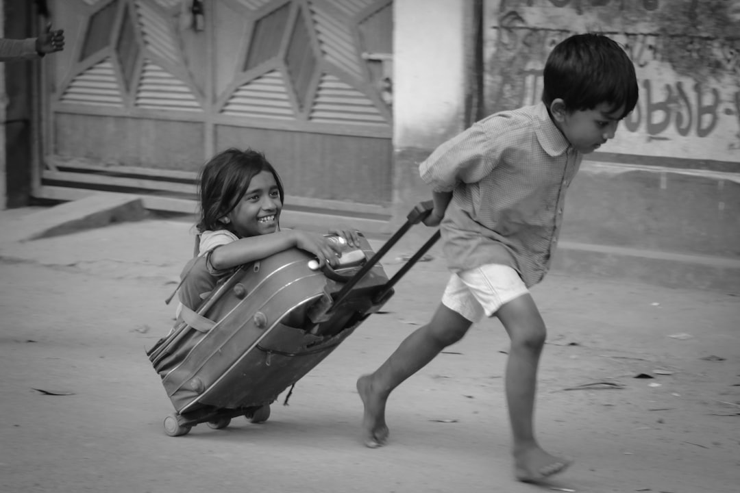 two young children playing with a suitcase on the street