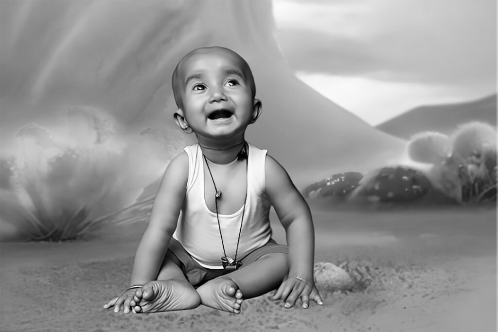 A happy baby sits on the ground looking up