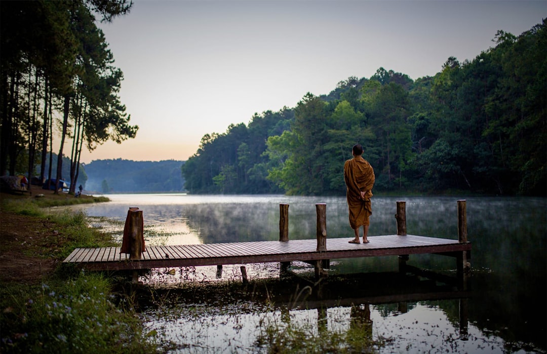 a man standing on a dock in front of a lake