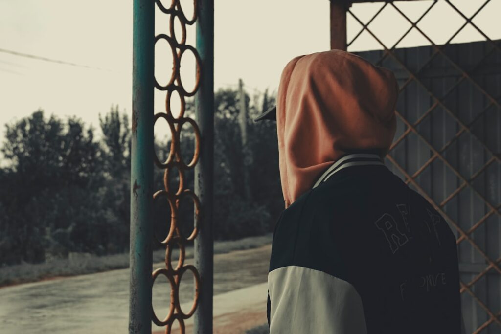 A person standing next to a metal fence