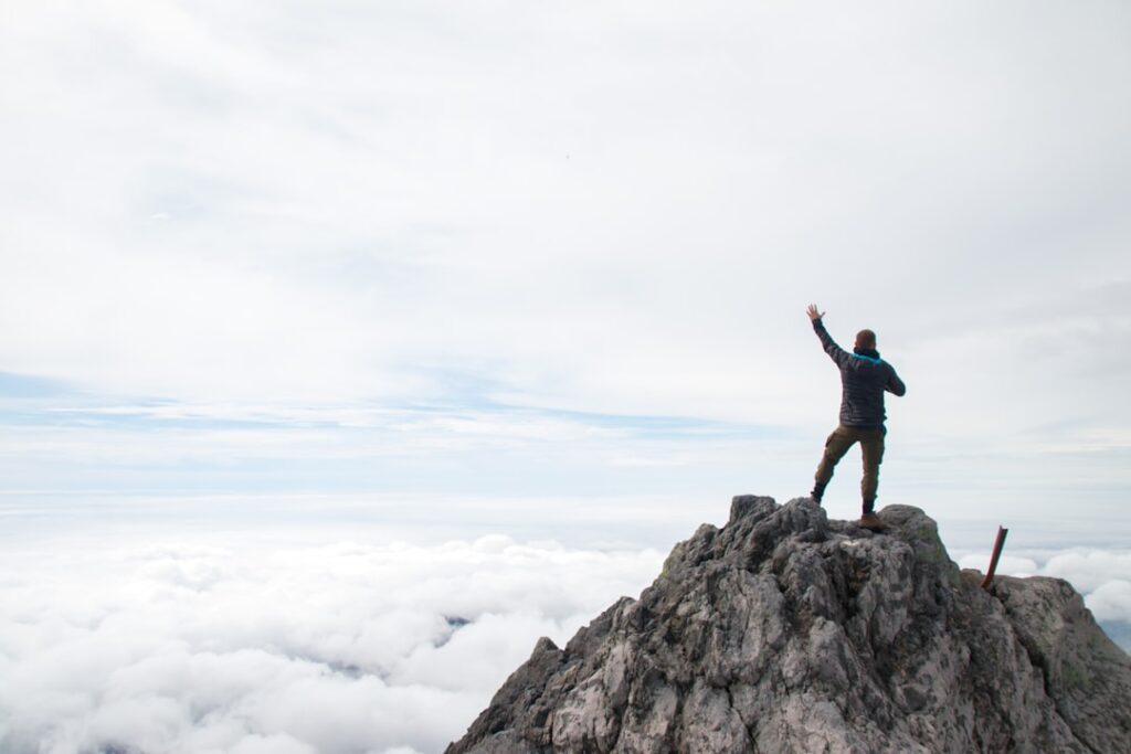 A man standing on top of a mountain with his arms in the air
