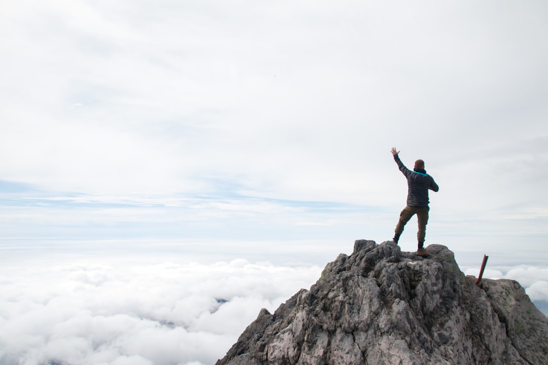 A man standing on top of a mountain with his arms in the air