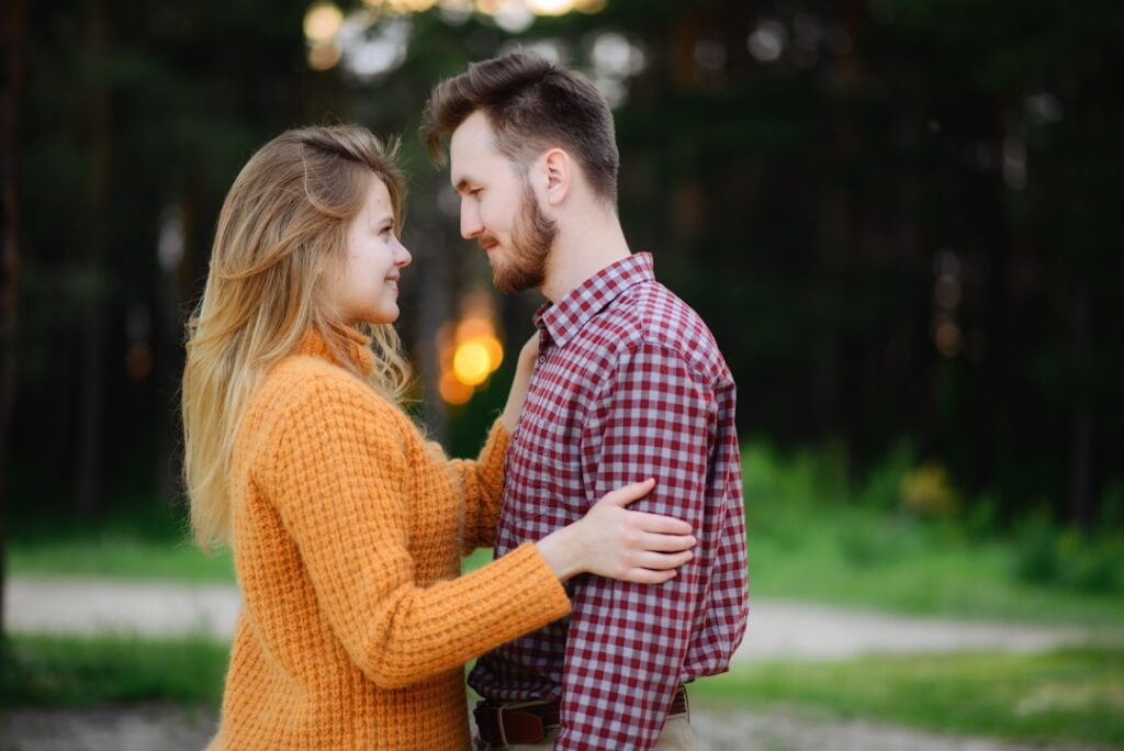 man and woman facing each other while standing near green field